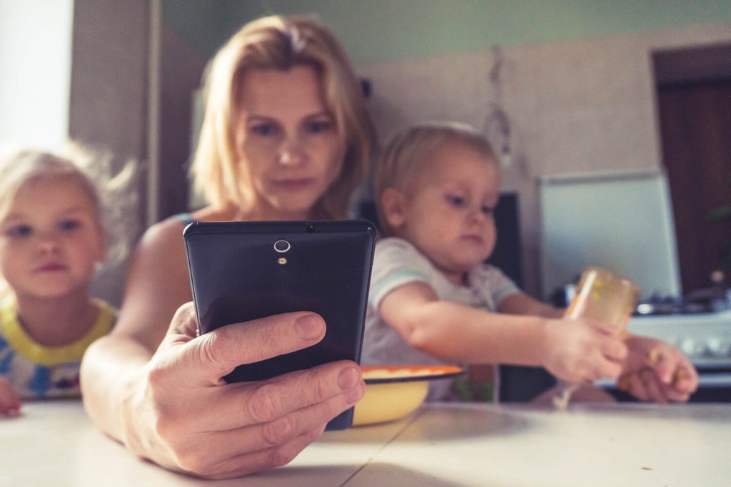 Barn och mamma som tittar på telefonen