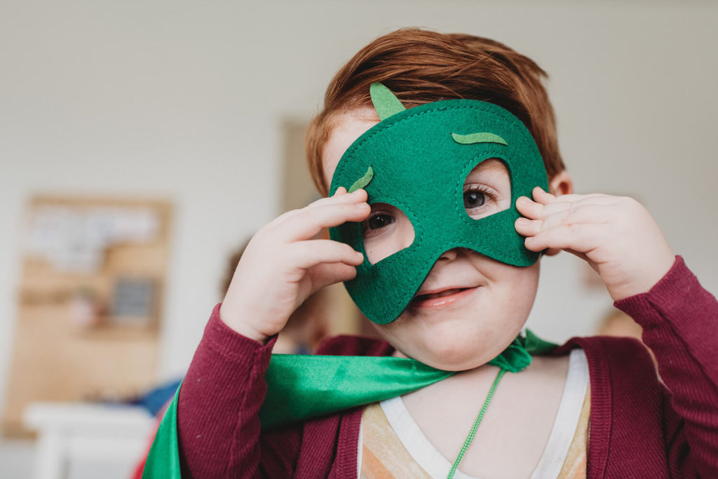 Barn håller grön mask för ansiktet