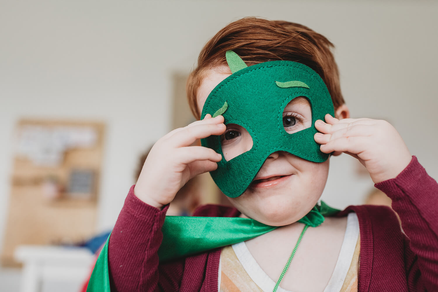 Barn håller grön mask för ansiktet